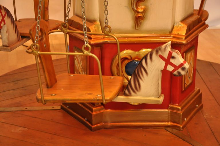 Kettenkarussell - Kettenflieger Detail eines Karussellpferdes mit Sattel, umgeben von bunten Verzierungen.