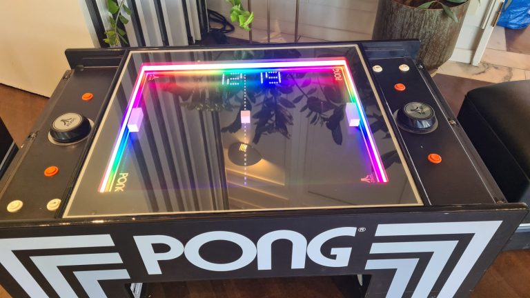 Schwarzer Tisch mit buntem LED-Rahmen und zwei Joysticks für das Spiel Pong.