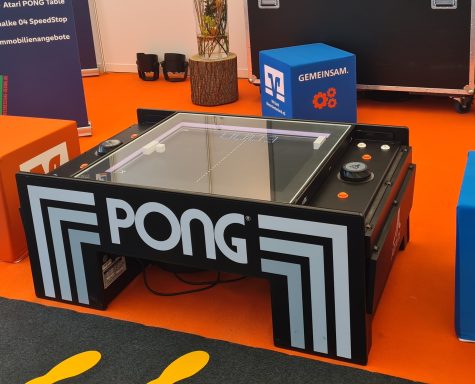 Tisch mit Pong-Spiel, schwarzer Rahmen, Glasoberfläche und bedruckten Tasten.