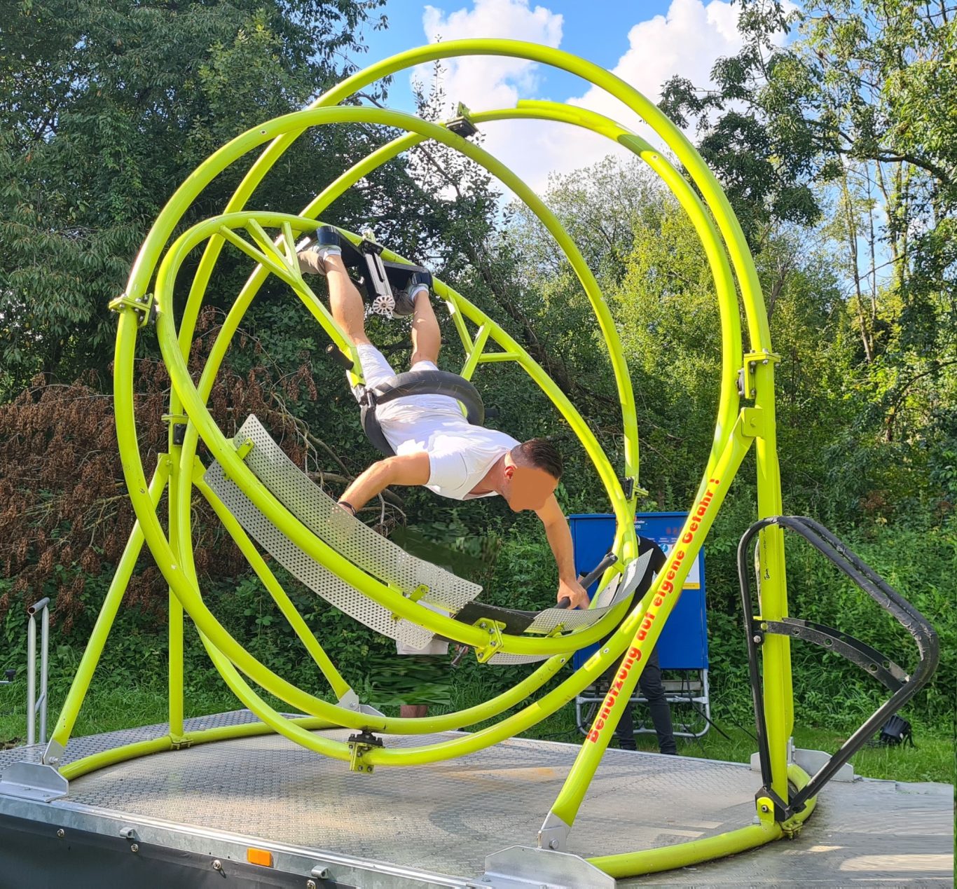 Aerotrim Person in Weiß nutzt eine grüne Sportanlage zum Schwingen und Trainieren.