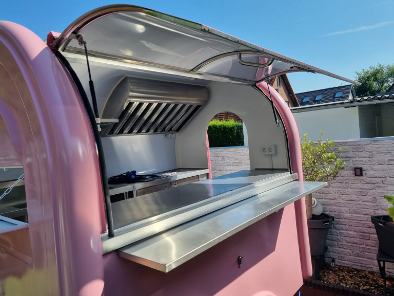 Pink Foodtruck mit geöffnetem Fenster und silberner Arbeitsfläche.